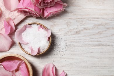 Photo of Flat lay composition with sea salt and beautiful petals of roses on white wooden table, space for text