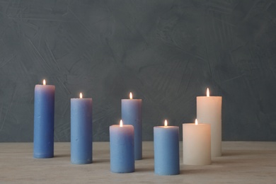 Burning candles on table against color wall