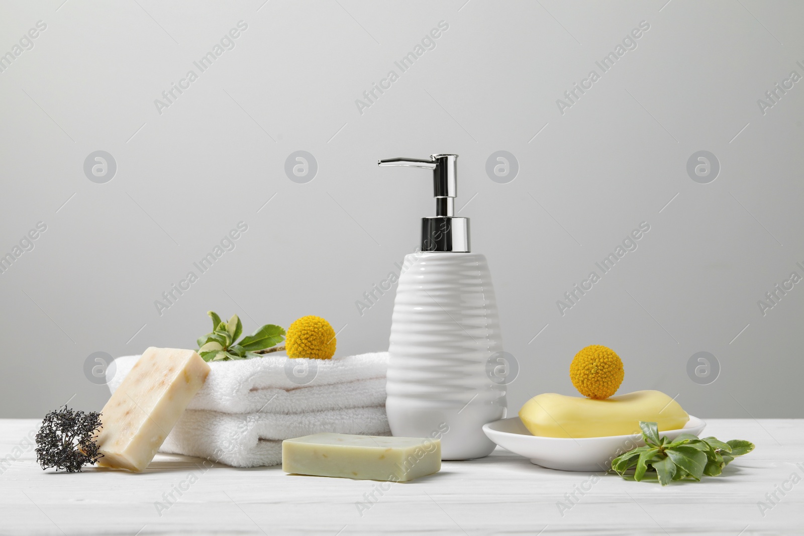 Photo of Soap bars, bottle dispenser and towels on wooden table against white background