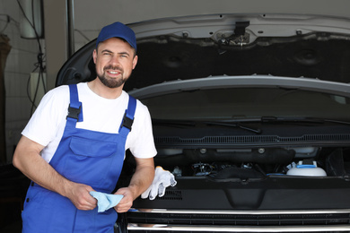 Professional auto mechanic near modern car in service center