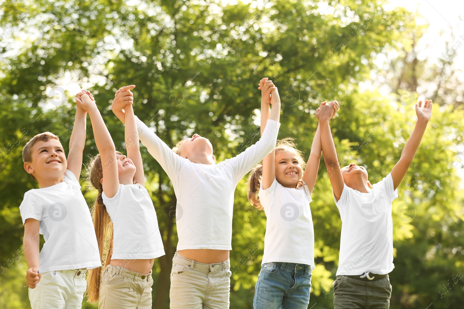 Photo of Group of children holding hands up in park. Volunteer project