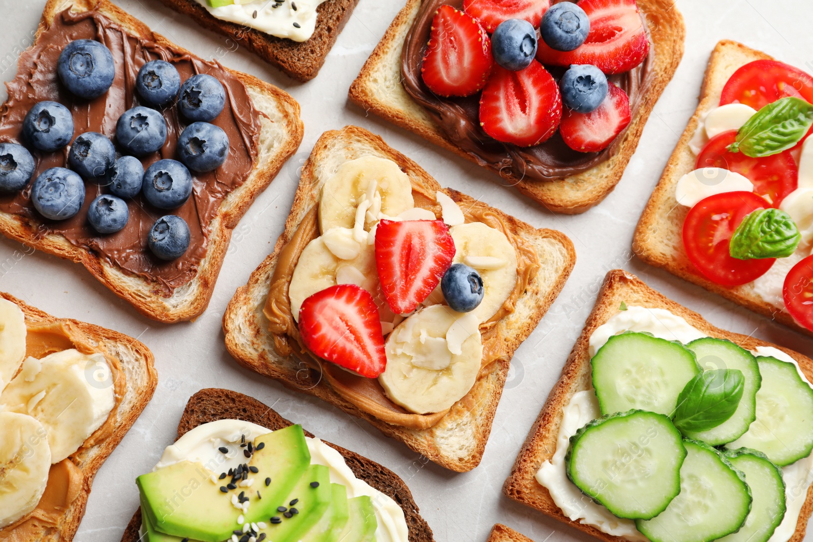 Photo of Tasty toast bread with fruits, berries and vegetables on light background, closeup