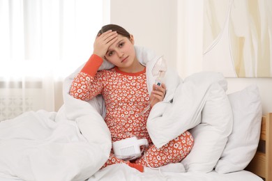 Sick girl holding nebulizer for inhalation on bed at home