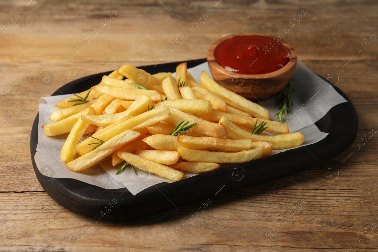 Photo of Delicious french fries served with ketchup on wooden table