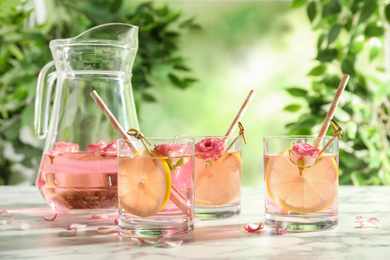 Photo of Refreshing drink with lemon and rose on white marble table