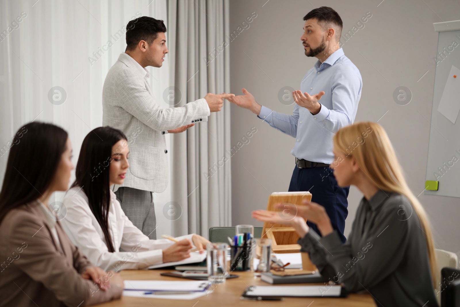 Photo of Angry coworkers quarreling at workplace in office