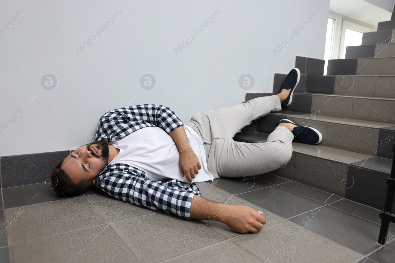 Photo of Unconscious man lying on floor after falling down stairs indoors