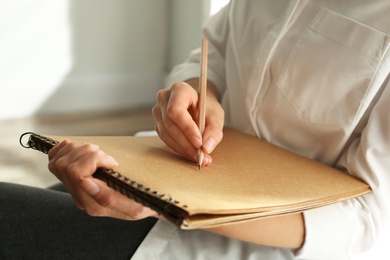 Photo of Woman drawing with pencil in notepad, closeup