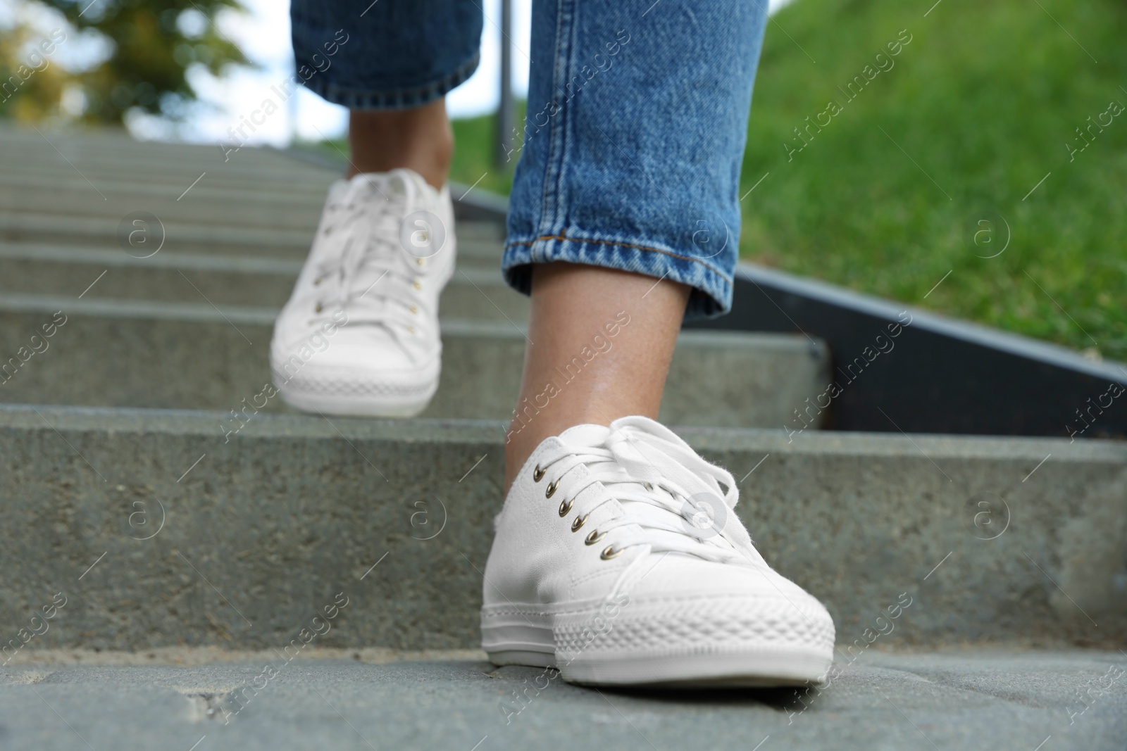 Photo of Woman in stylish black sneakers walking down stairs, closeup