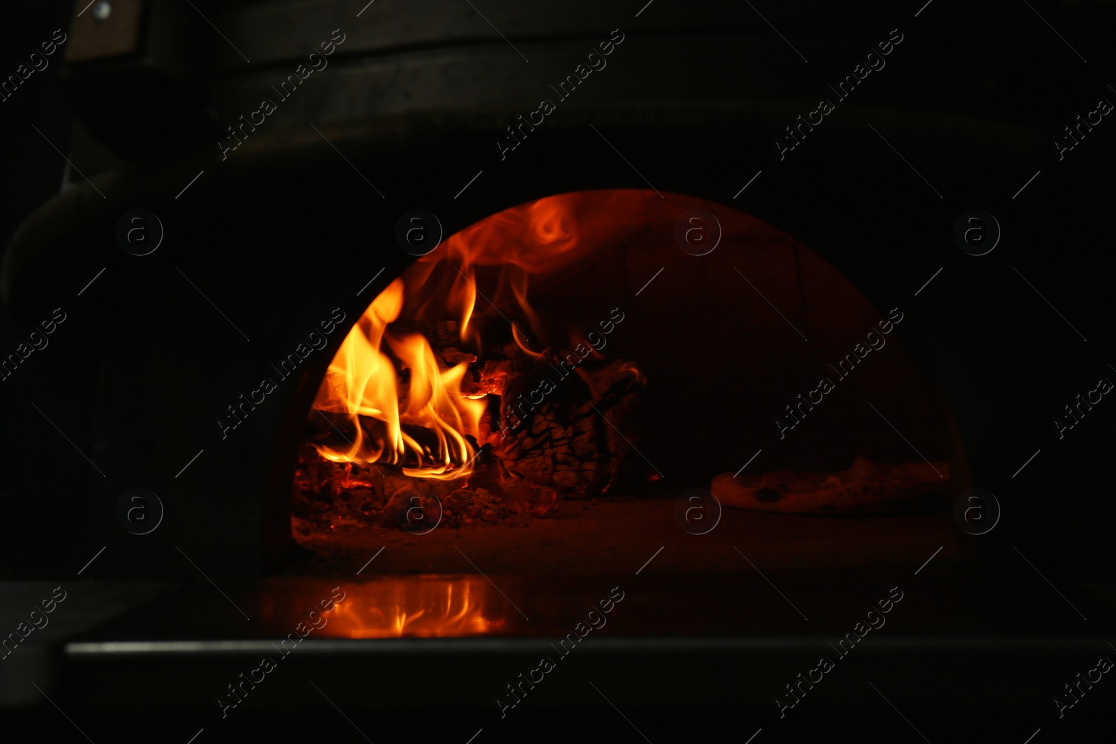 Photo of Oven with burning firewood and tasty pizza in restaurant kitchen