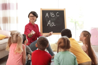 Photo of Young woman teaching little children indoors. Learning by playing