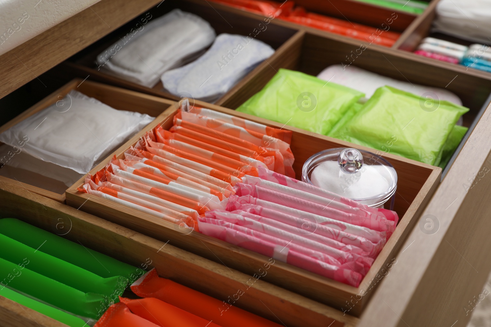 Photo of Storage of different feminine hygiene products in wooden drawer, closeup