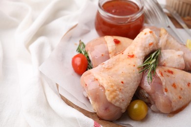 Photo of Marinade, raw chicken drumsticks, rosemary and tomatoes on table, closeup. Space for text