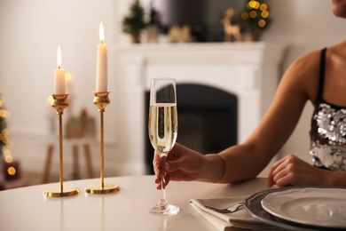 Photo of Woman with glass of champagne at table indoors, closeup