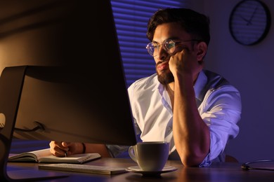 Photo of Tired young man working late in office