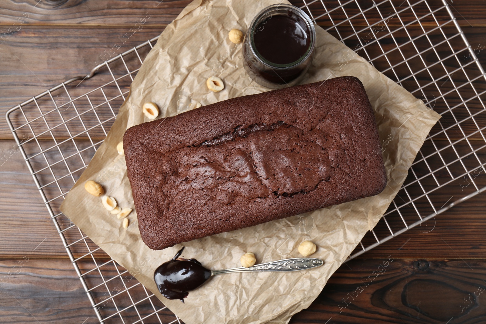 Photo of Delicious chocolate sponge cake, nuts and glaze on wooden table, flat lay