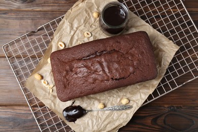 Delicious chocolate sponge cake, nuts and glaze on wooden table, flat lay