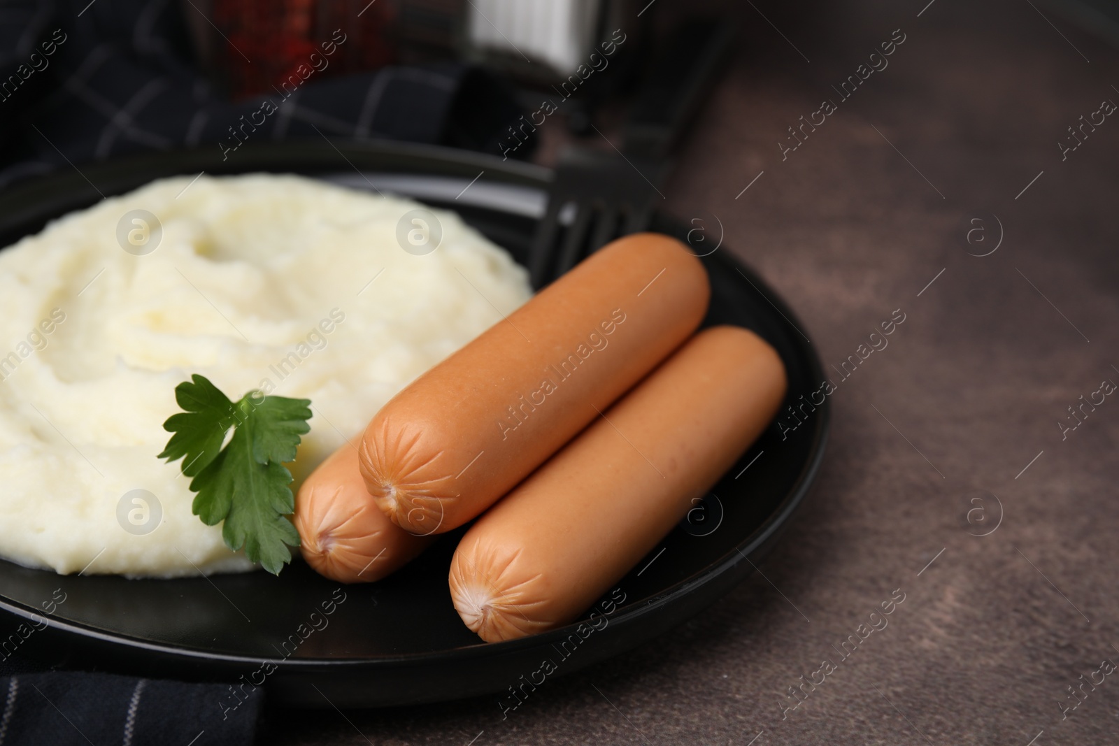 Photo of Delicious boiled sausages, mashed potato and parsley on brown table, closeup