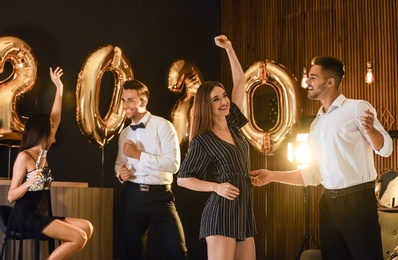 Young people celebrating New Year in club. Golden 2020 balloons on background