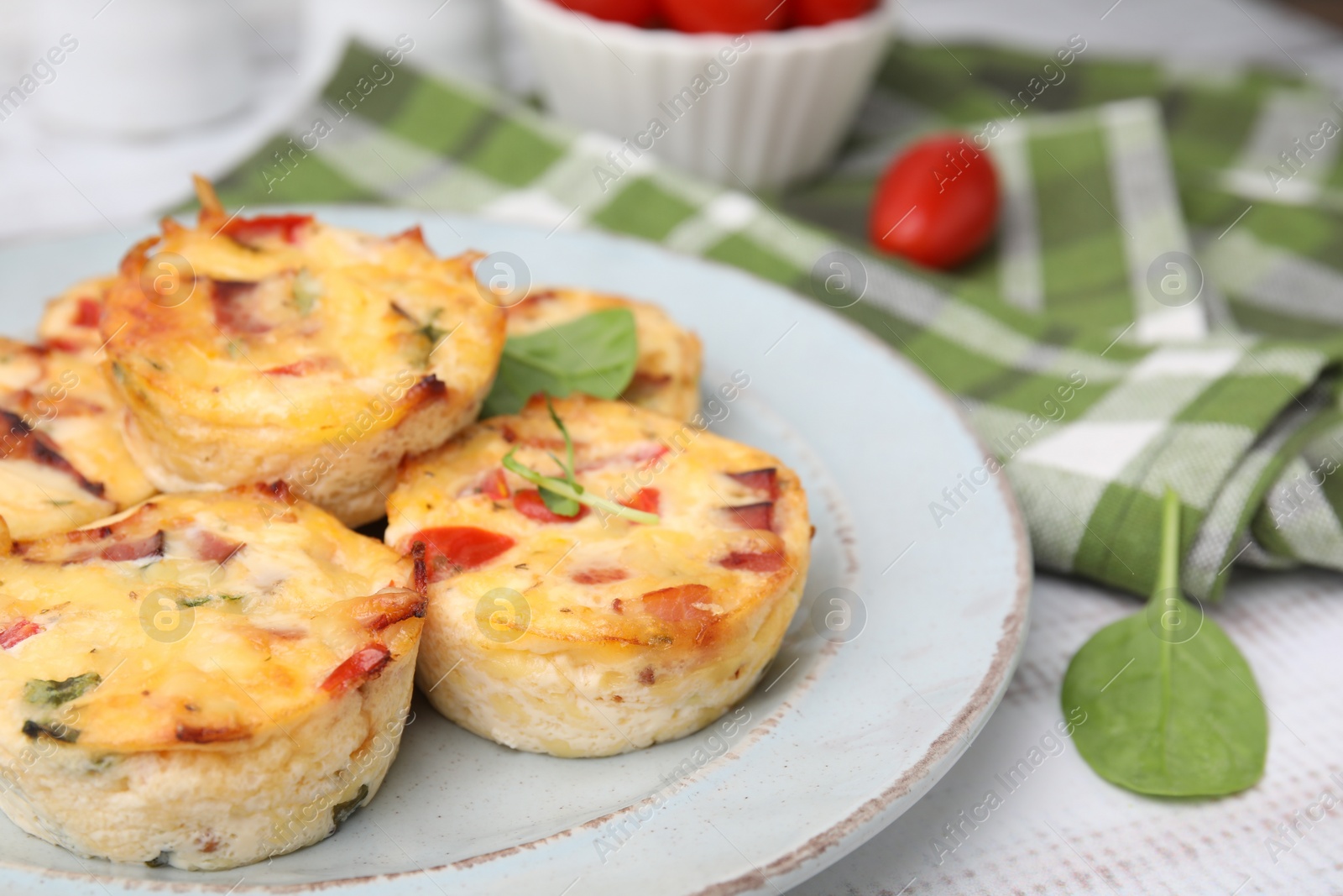 Photo of Delicious egg muffins with cheese and bacon on white wooden table, closeup. Space for text