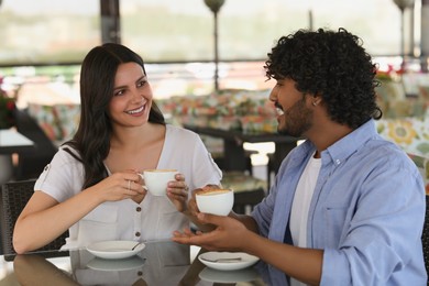 International dating. Happy couple enjoying tasty coffee in cafe