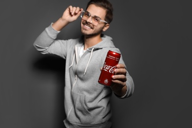 MYKOLAIV, UKRAINE - NOVEMBER 28, 2018: Young man with Coca-Cola can on dark background