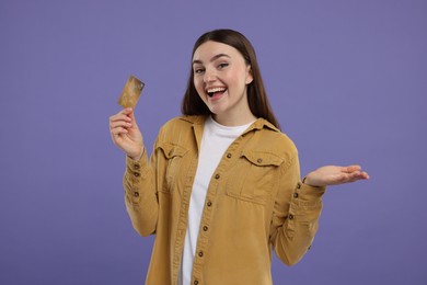 Photo of Happy woman with credit card on purple background