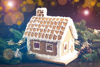 Image of Beautiful gingerbread house decorated with icing and fir branch on wooden table