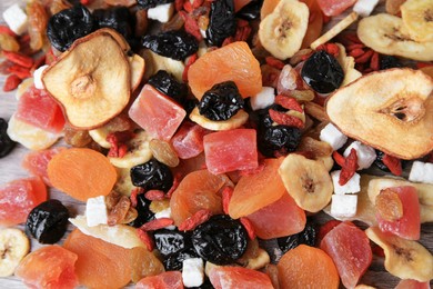 Photo of Pile of different tasty dried fruits on wooden table, flat lay