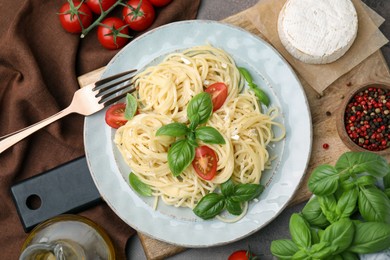 Delicious pasta with brie cheese, tomatoes and basil leaves served on table, flat lay