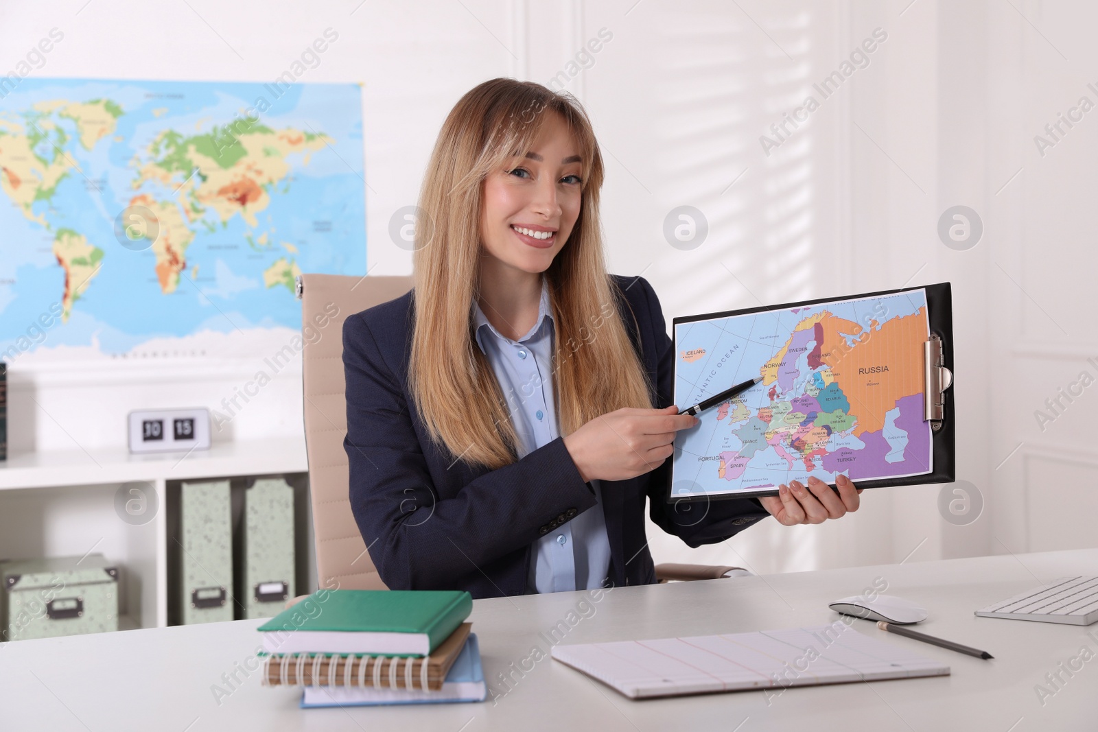 Photo of Happy manager showing map at desk in travel agency
