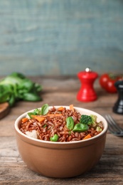 Photo of Bowl of brown rice with vegetables on wooden table, space for text