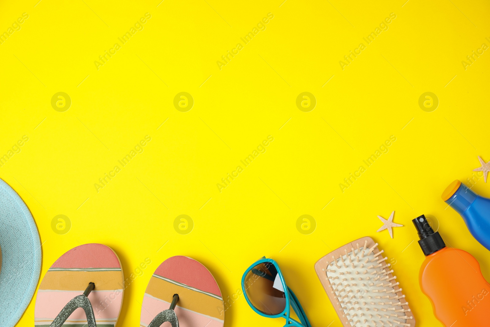 Photo of Flat lay composition with beach accessories on yellow background, space for text