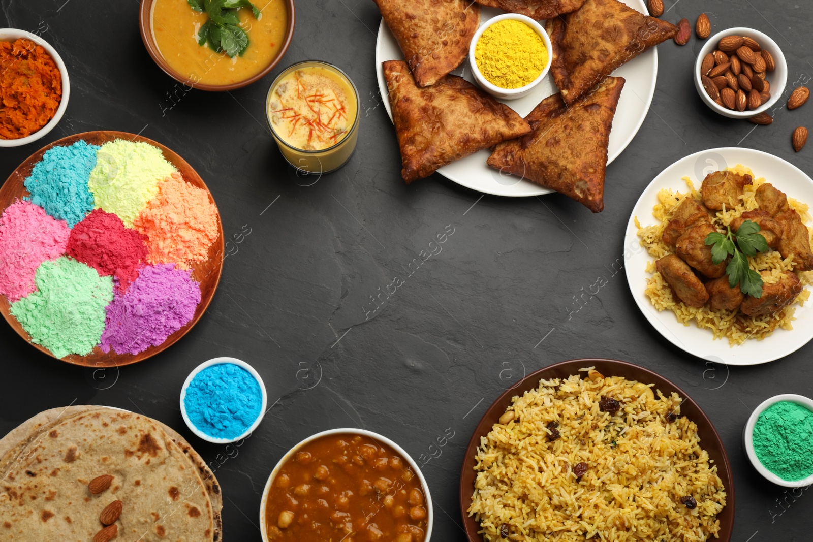 Photo of Frame of traditional Indian food and color powders on black table, flat lay with space for text. Holi festival celebration