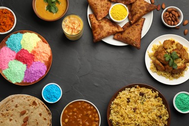 Frame of traditional Indian food and color powders on black table, flat lay with space for text. Holi festival celebration