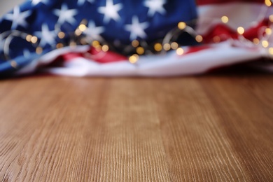 Photo of Blurred American flag and garland on wooden table. Space for text