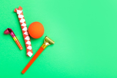 Photo of Party blowers, clown nose and chinese finger trap on green background, flat lay. Space for text