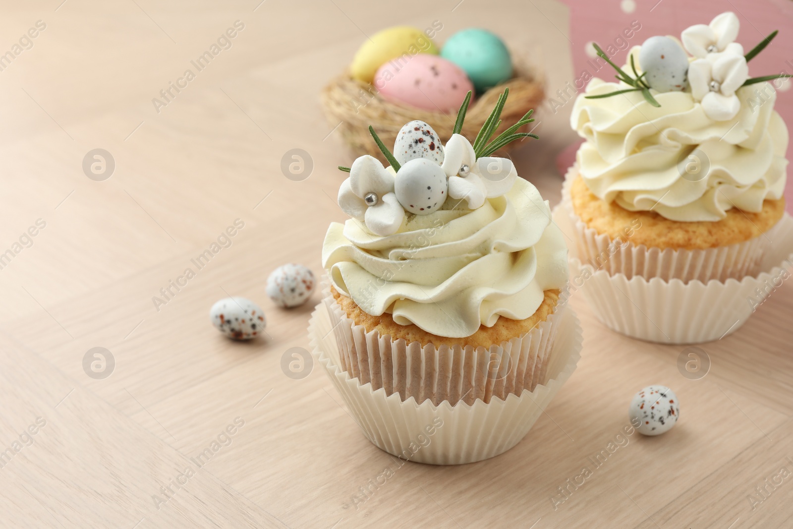 Photo of Tasty Easter cupcakes with vanilla cream on wooden table, closeup. Space for text