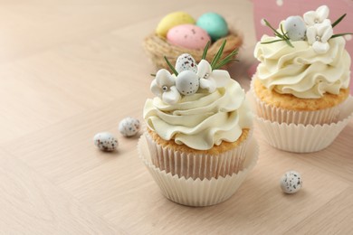 Photo of Tasty Easter cupcakes with vanilla cream on wooden table, closeup. Space for text