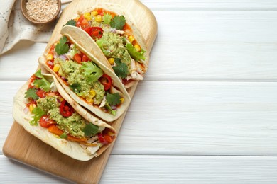 Photo of Delicious tacos with guacamole, meat and vegetables served on white wooden table, top view. Space for text