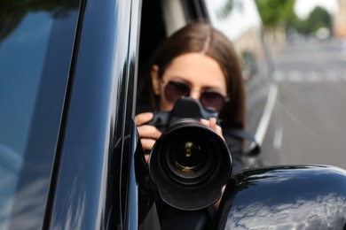 Private detective with camera spying from car, focus on lens