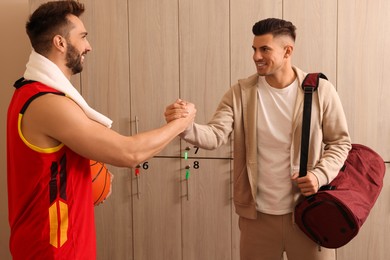 Photo of Handsome men greeting each other in locker room
