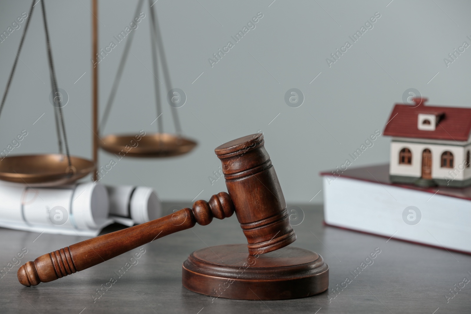 Photo of Construction and land law concepts. Judge gavel, scales of justice, book, drawings with house model on grey table