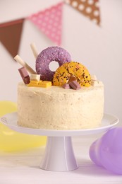 Photo of Delicious cake decorated with sweets on white wooden table