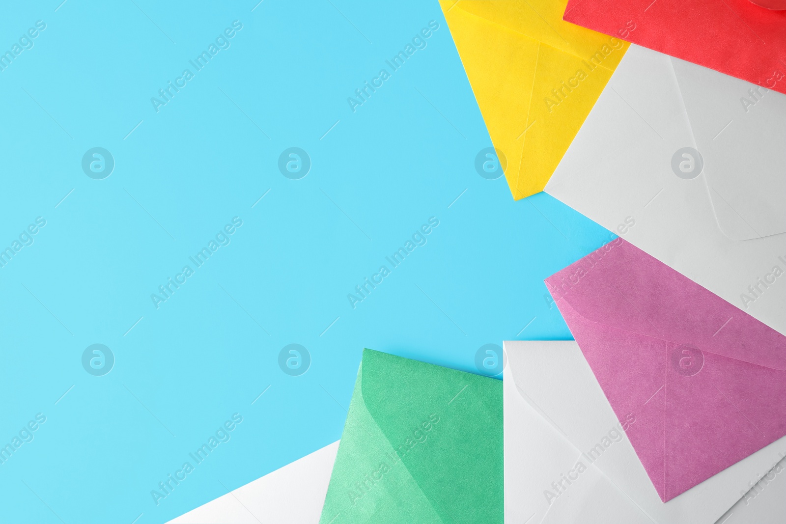 Photo of Colorful paper envelopes on light blue background, flat lay. Space for text