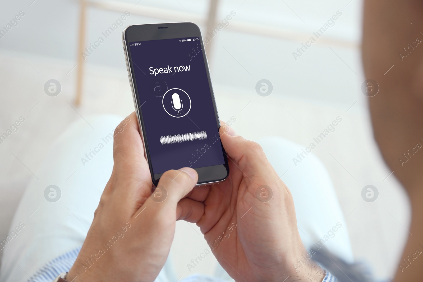 Image of Man using voice search on smartphone indoors, closeup