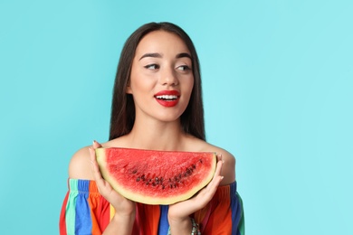 Beautiful young woman posing with watermelon on color background