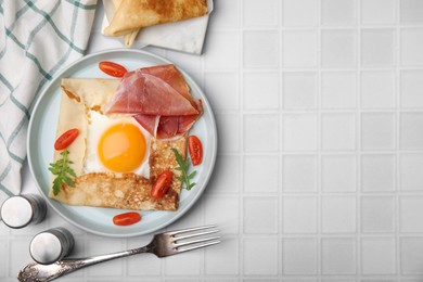 Photo of Delicious crepe with egg served on white tiled table, flat lay with space for text. Breton galette