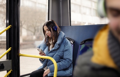 Photo of Young woman listening to music with headphones in public transport