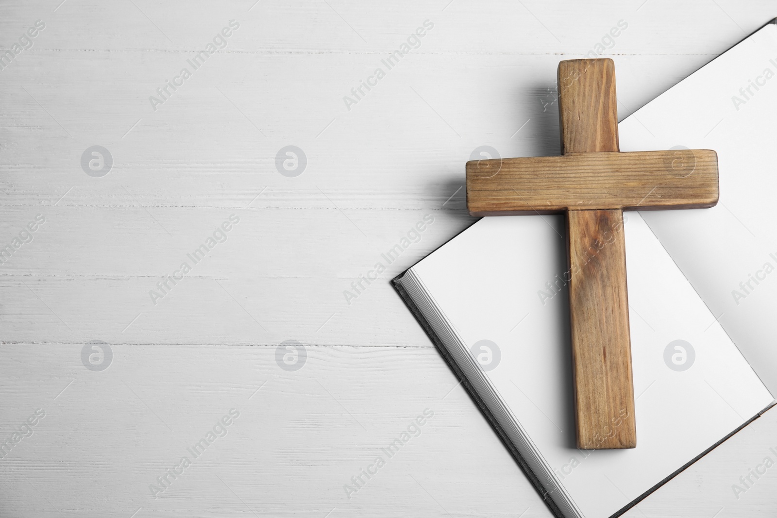 Photo of Christian cross and Bible on white wooden background, flat lay with space for text. Religion concept